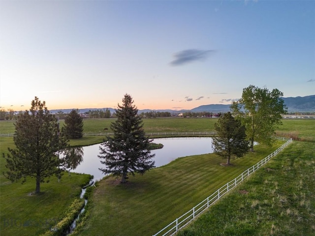 property view of water with fence, a mountain view, and a rural view