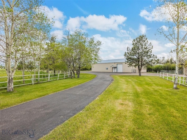 view of front of property with an outbuilding, a front lawn, a detached garage, and fence