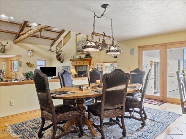 dining space featuring a textured ceiling, a lit fireplace, and french doors