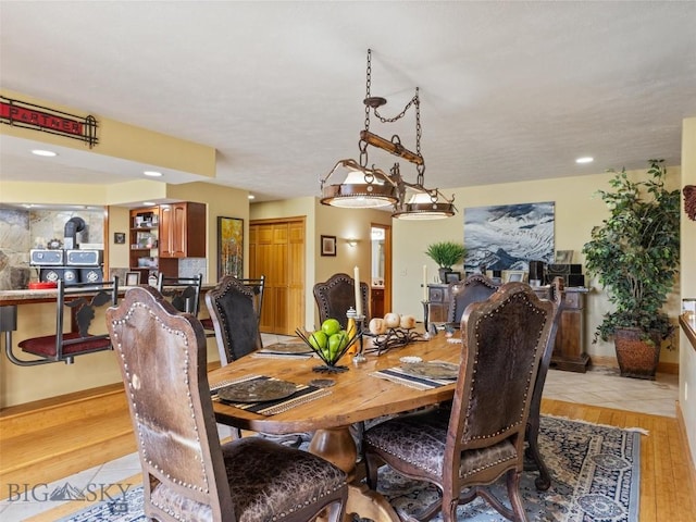 dining area with light wood-type flooring, a wood stove, and baseboards