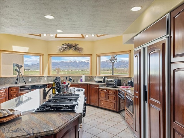 kitchen with a toaster, a textured ceiling, decorative backsplash, and light tile patterned flooring