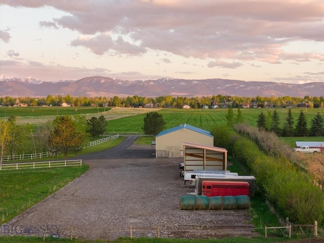 view of property's community featuring a rural view, a mountain view, and an outbuilding