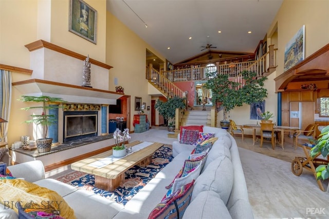 5275 Riverview Dr, Helena, MT 59602 - carpeted living area featuring stairway, high vaulted ceiling, healthy amount of natural light, a ceiling fan, and a high end fireplace