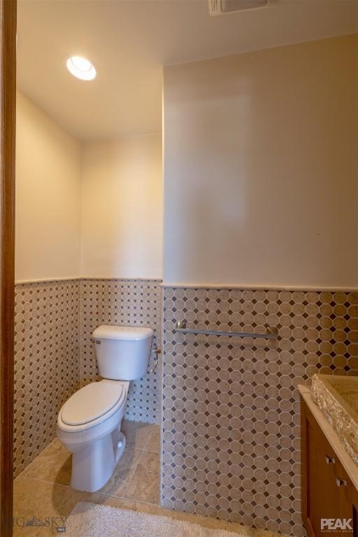 5275 Riverview Dr, Helena, MT 59602 - half bathroom featuring wainscoting, vanity, tile walls, and tile patterned flooring