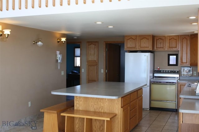 kitchen with stove, light tile patterned floors, white refrigerator, a chandelier, and a center island