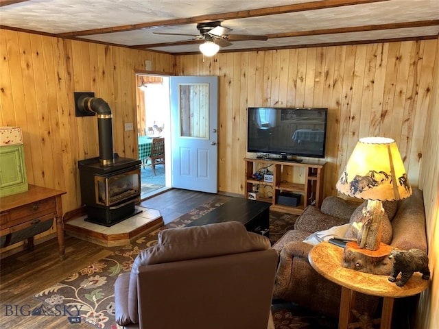 living room featuring ceiling fan, wooden walls, hardwood / wood-style flooring, and a wood stove