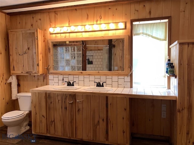 bathroom with hardwood / wood-style floors, dual vanity, wood walls, toilet, and backsplash