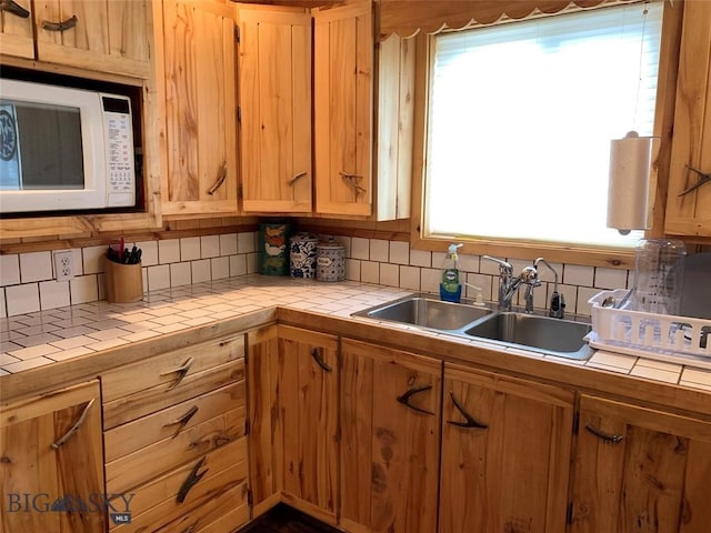 kitchen with tile counters, tasteful backsplash, and sink