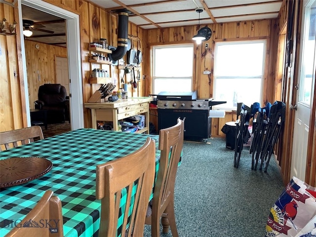 dining area featuring a healthy amount of sunlight, ceiling fan, and wooden walls