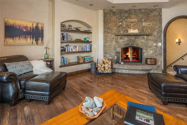 living room with built in shelves, wood-type flooring, and a fireplace