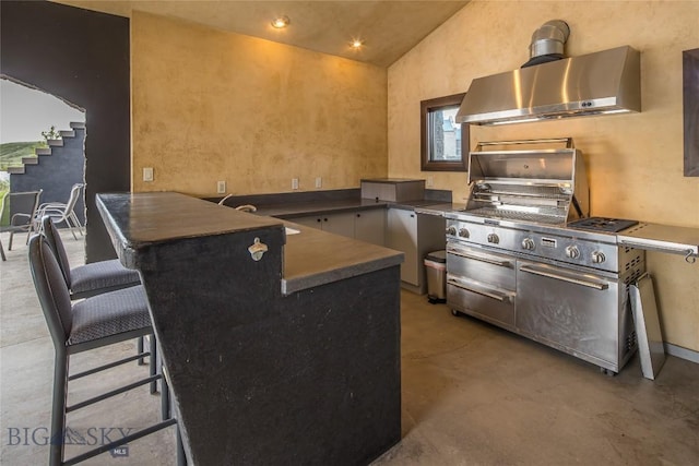 kitchen featuring kitchen peninsula, concrete flooring, a breakfast bar, wall chimney exhaust hood, and lofted ceiling