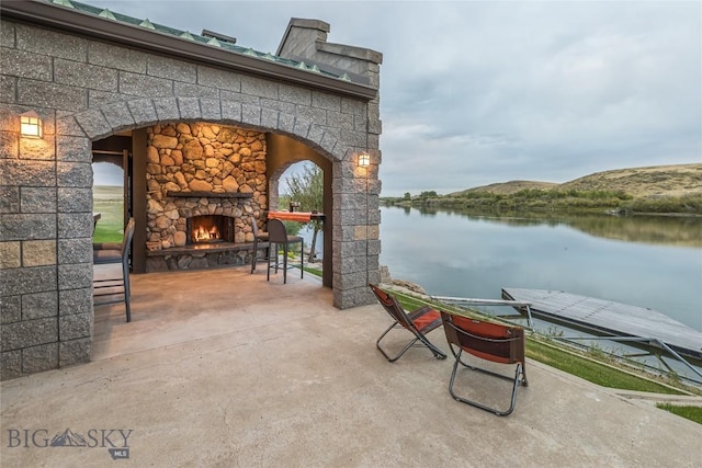 view of patio / terrace with a water and mountain view and an outdoor stone fireplace