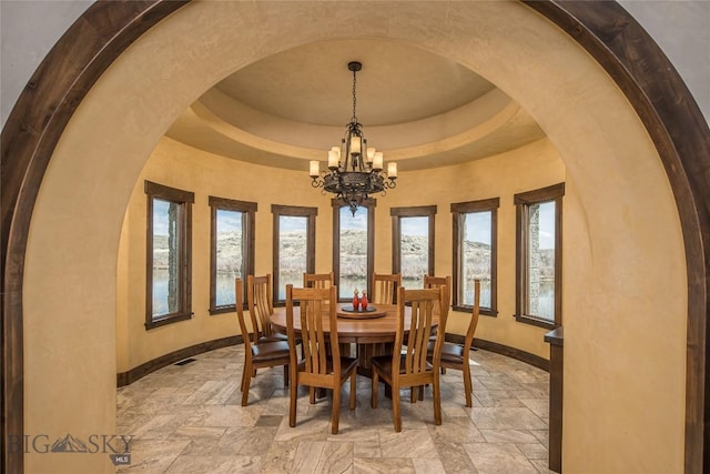 dining room with a raised ceiling and a chandelier