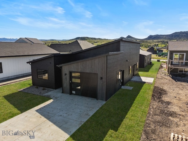 view of property exterior with a patio, a mountain view, and a yard