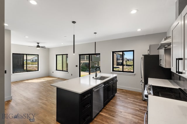 kitchen featuring wall chimney range hood, dark hardwood / wood-style flooring, range with electric stovetop, sink, and dishwasher