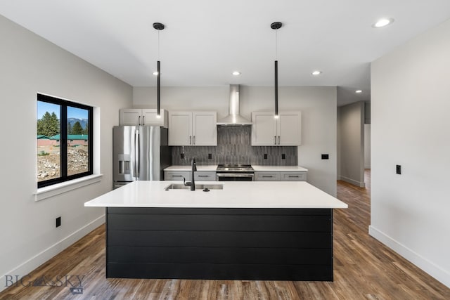 kitchen featuring wall chimney range hood, hanging light fixtures, stainless steel appliances, hardwood / wood-style flooring, and tasteful backsplash