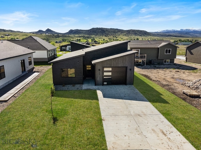 view of front of property featuring a garage, a front yard, and a mountain view