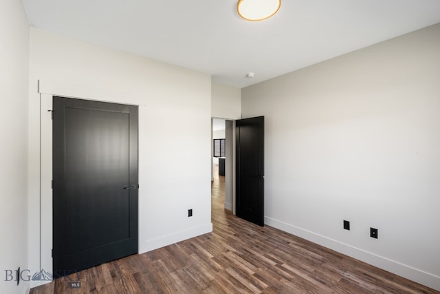 unfurnished bedroom featuring a closet and dark hardwood / wood-style floors