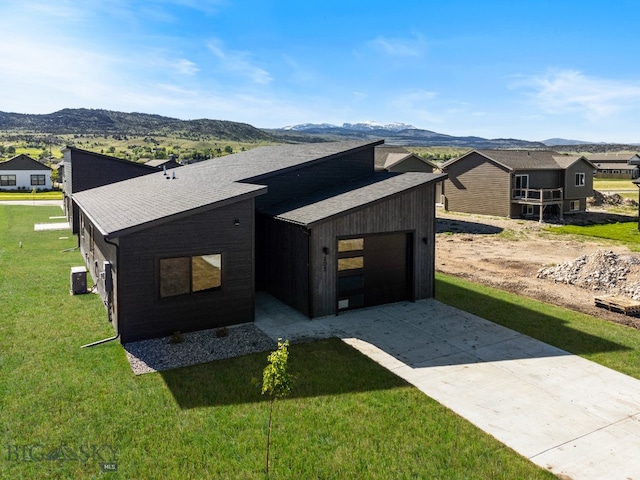 view of front of property featuring a front yard, a garage, and a mountain view