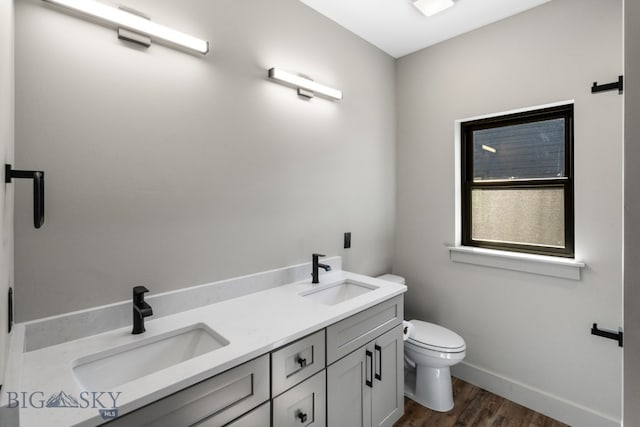 bathroom featuring double vanity, toilet, and hardwood / wood-style floors