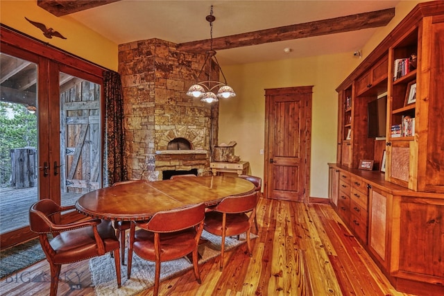 dining room featuring beam ceiling, french doors, a fireplace, and wood-type flooring