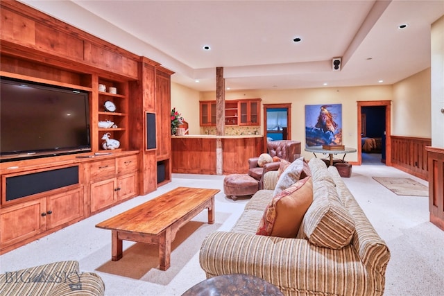 living room featuring light carpet, built in shelves, and a raised ceiling