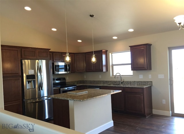 kitchen with hanging light fixtures, plenty of natural light, a kitchen island, and appliances with stainless steel finishes