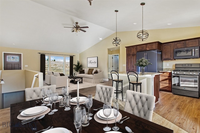 dining room featuring high vaulted ceiling, ceiling fan, and light wood-type flooring