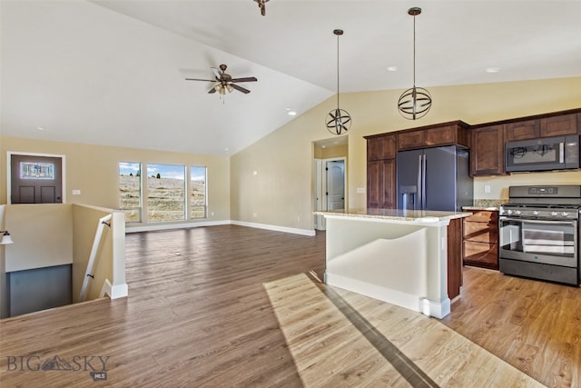 kitchen featuring hanging light fixtures, light hardwood / wood-style flooring, light stone counters, and appliances with stainless steel finishes