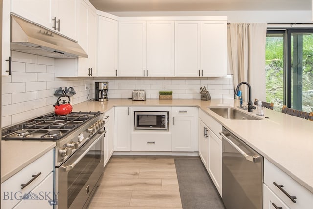 kitchen with appliances with stainless steel finishes, white cabinetry, sink, and backsplash