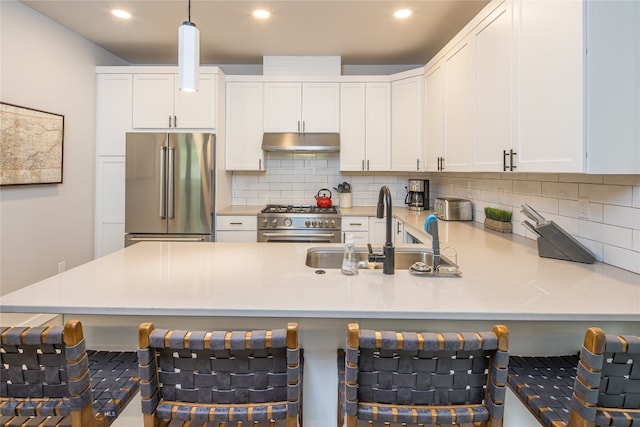 kitchen with tasteful backsplash, premium appliances, a kitchen bar, and pendant lighting