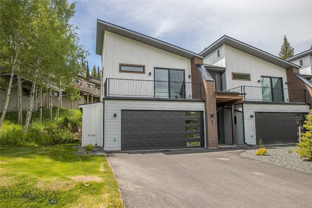 view of front of house with a front yard, a garage, and a balcony