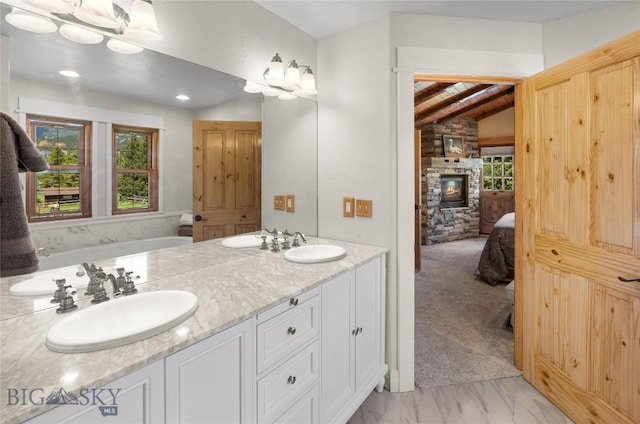 201 Silver Run Rd, Gallatin Gateway, MT 59730 - ensuite bathroom with a stone fireplace, a bathtub, double vanity, and lofted ceiling