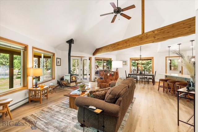 living room with light wood-type flooring, ceiling fan with notable chandelier, a wood stove, a baseboard heating unit, and high vaulted ceiling