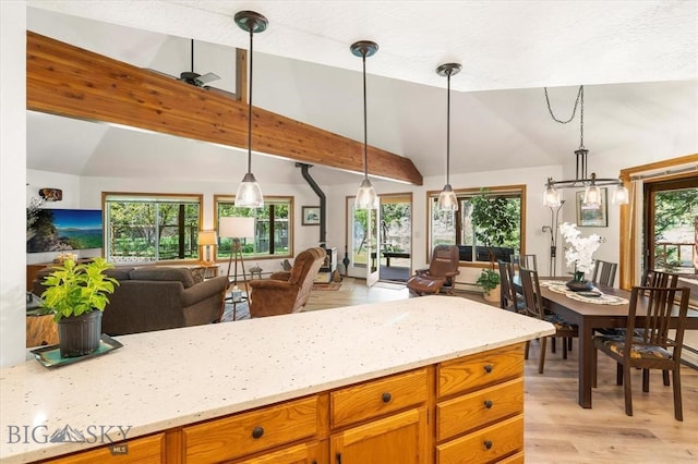 kitchen with light stone countertops, lofted ceiling, light hardwood / wood-style flooring, and decorative light fixtures