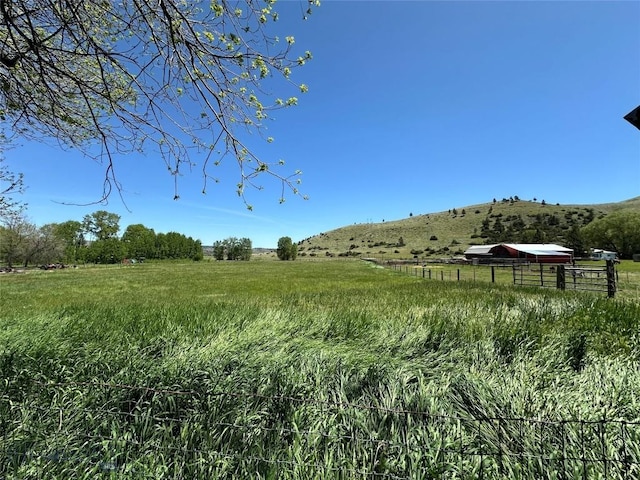 view of yard with fence and a rural view