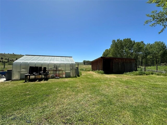 view of yard featuring an outdoor structure and a greenhouse