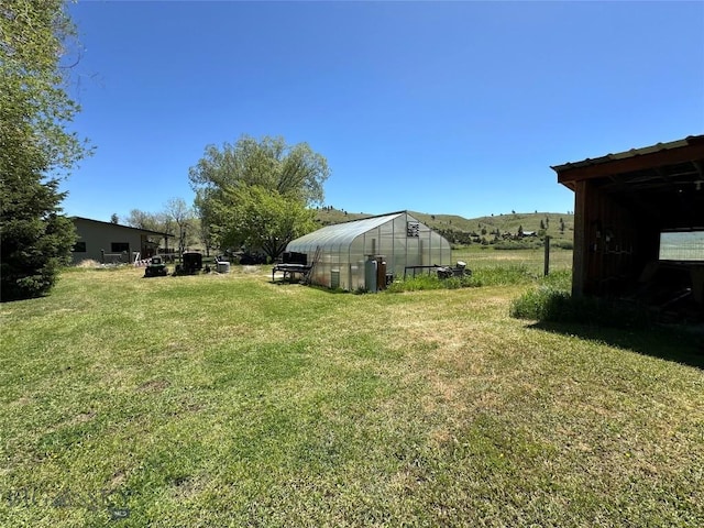 view of yard featuring an outdoor structure and a greenhouse