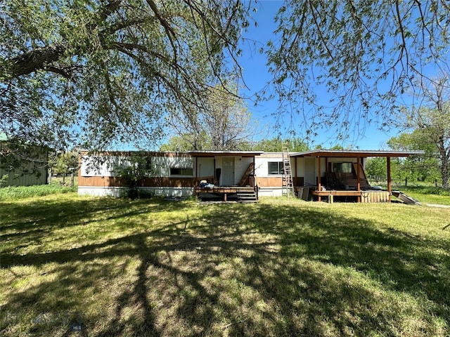 rear view of house featuring a wooden deck and a lawn