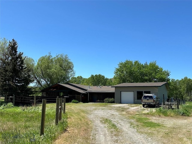 view of front of home with fence, dirt driveway, and an attached garage