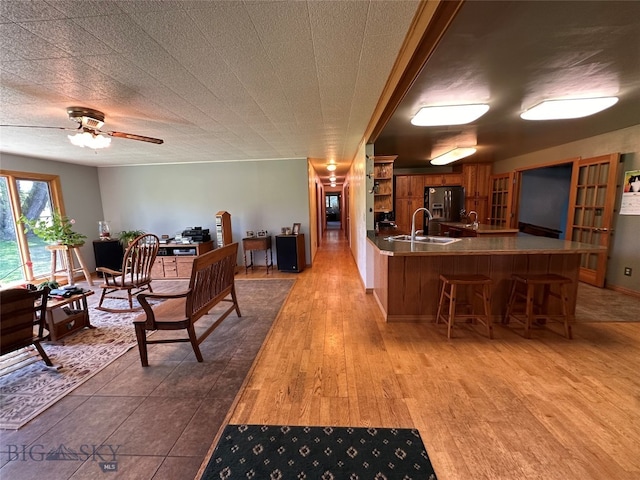 interior space featuring light hardwood / wood-style flooring, a kitchen breakfast bar, kitchen peninsula, sink, and ceiling fan