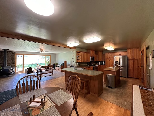 dining space with a wood stove, ceiling fan, sink, and light wood-type flooring