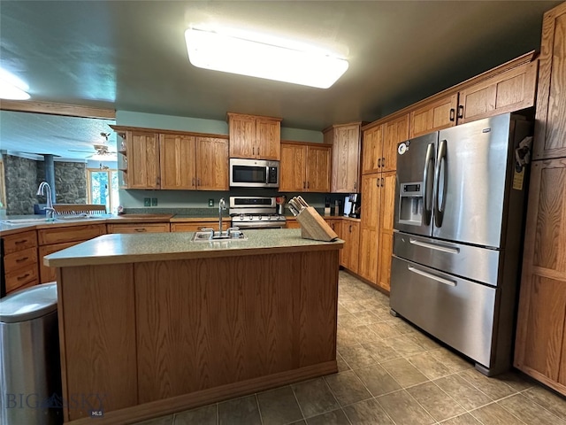 kitchen featuring sink, appliances with stainless steel finishes, an island with sink, and ceiling fan