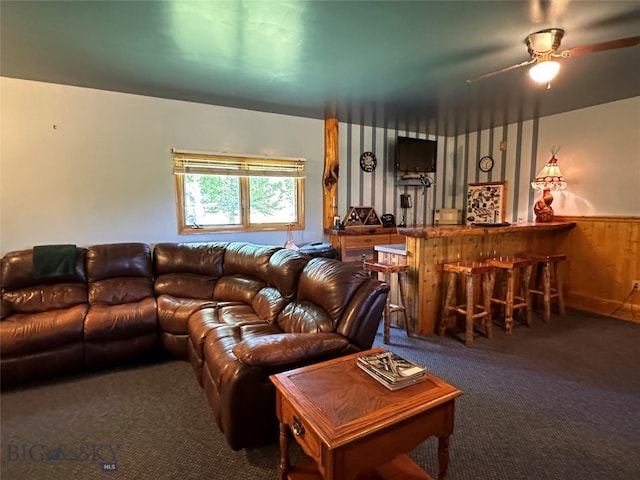 living room with bar area, carpet, ceiling fan, and wooden walls