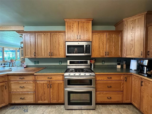 kitchen featuring brown cabinets, stainless steel appliances, and dark countertops