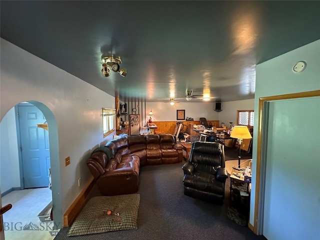 carpeted living room with arched walkways and ceiling fan