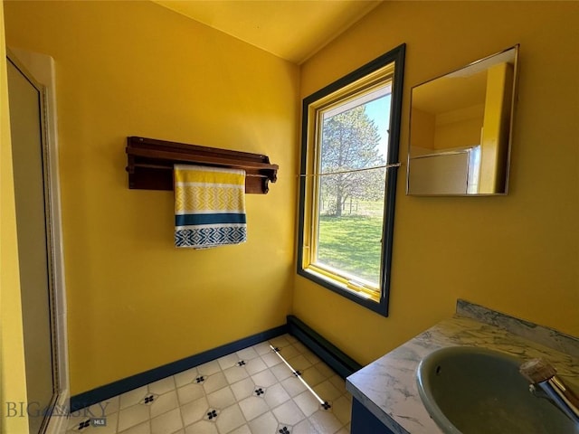bathroom with a healthy amount of sunlight, baseboards, a shower with shower door, and vanity