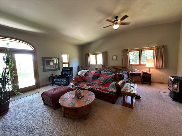 bedroom featuring multiple windows, ceiling fan, a wood stove, and access to outside