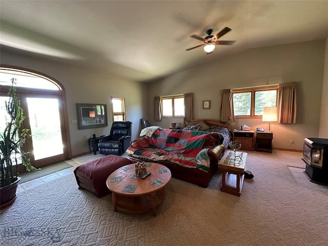 living area featuring ceiling fan, a wood stove, vaulted ceiling, and light carpet