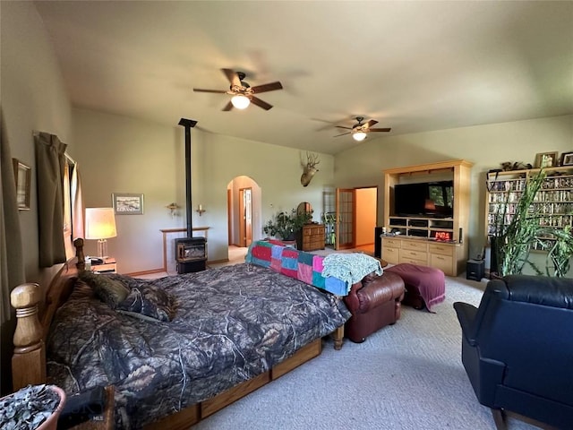 carpeted bedroom with arched walkways, ceiling fan, and a wood stove